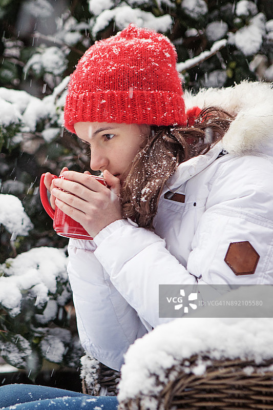 美丽的黑发少女穿着白色滑雪服在下雪的冬天户外设置图片素材