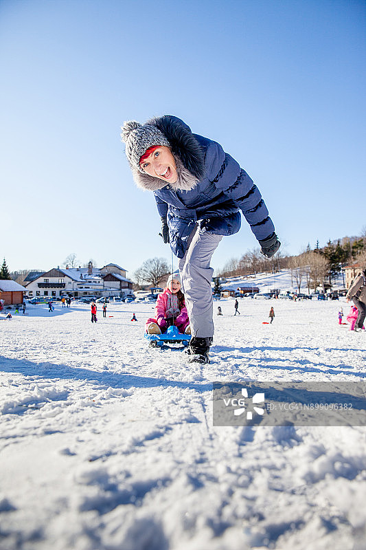 快乐的母亲和女儿在雪橇上玩在冬天的风景图片素材