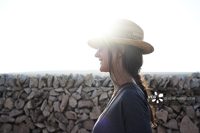西班牙，梅诺卡，带着草帽背光微笑的单身旅行者图片素材