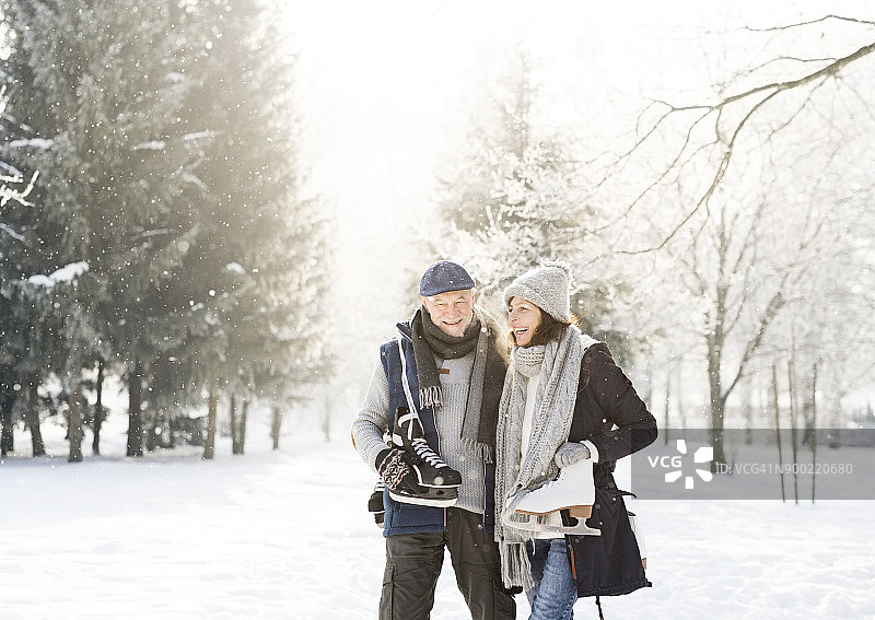 一对快乐的老年夫妇穿着溜冰鞋在冬天的风景里散步图片素材