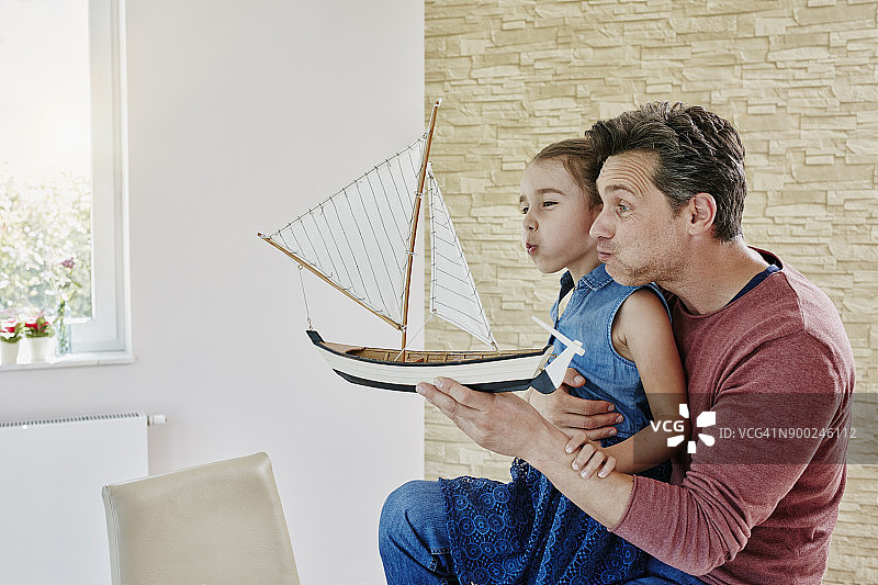 快乐的爸爸和女儿在家里玩模型船图片素材