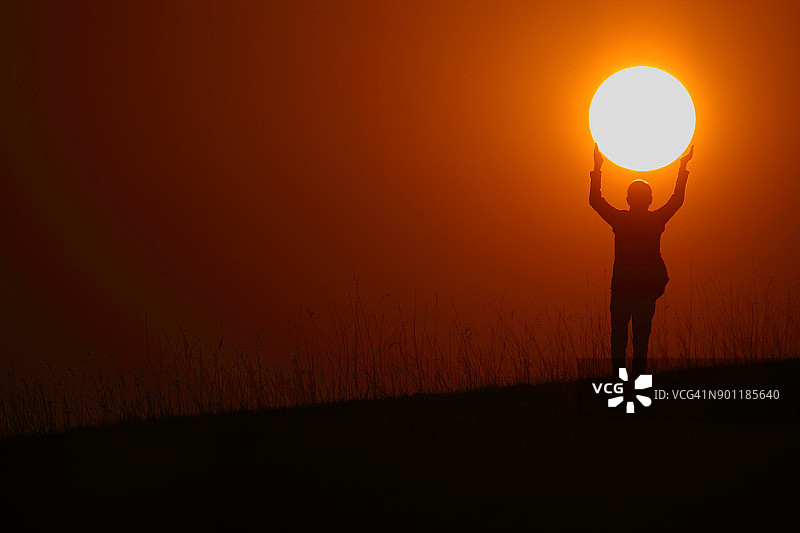 一个徒步旅行者双手捧着太阳的剪影图片素材