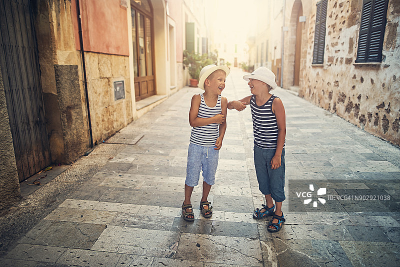 快乐的游客男孩在地中海的街道上散步和欢笑。图片素材