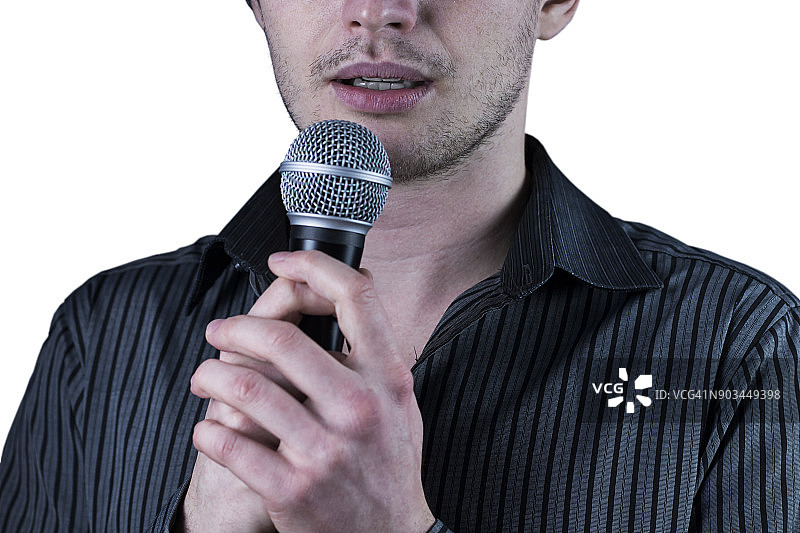 一个男人对着白色背景的麦克风说话的正面视图。图片素材