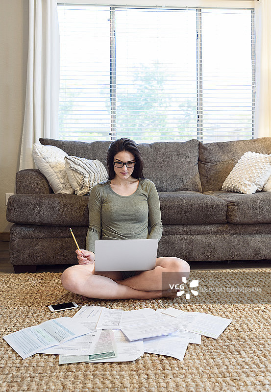 一个白人女人坐在地板上用笔记本电脑写文件图片素材
