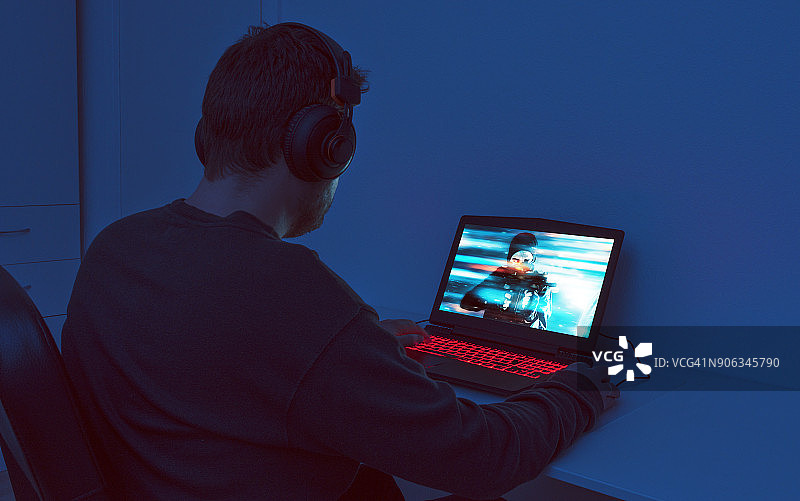 男人在他的游戏笔记本电脑上玩动作游戏图片素材