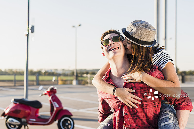 幸福的年轻夫妇拥抱在停车场水平与摩托车的背景图片素材