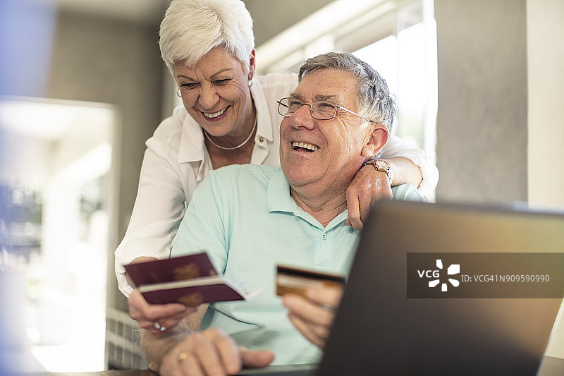 快乐的老年夫妇拿着护照一起在网上预订他们的旅行图片素材