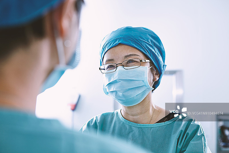 从肩膀上看，手术团队穿着手术服正在产科病房手术室讨论图片素材