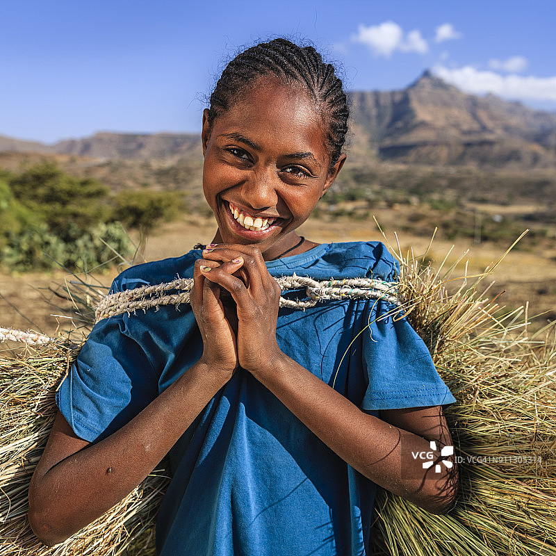东非，非洲年轻女孩扛着稻草图片素材