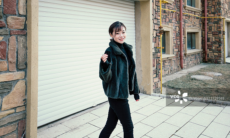 穿着黑色皮草大衣的中国时髦女人在街上图片素材