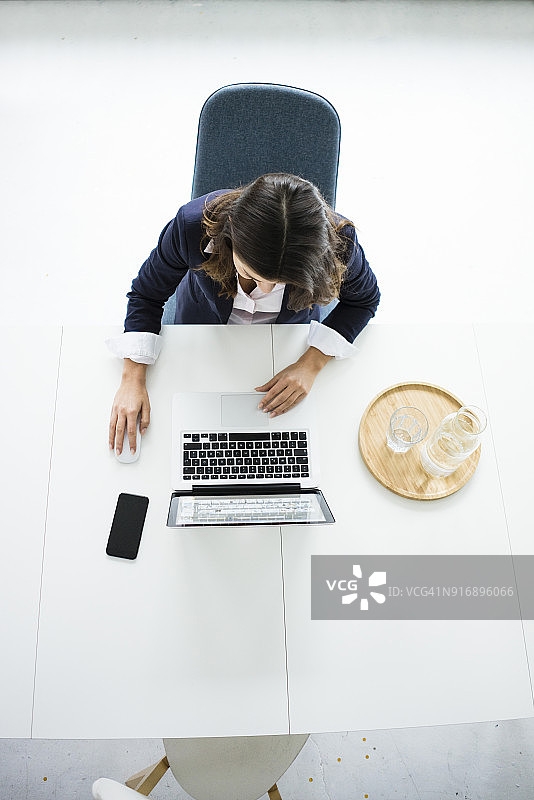 女商人坐在办公室的办公桌前用手提电脑工作，俯视图图片素材