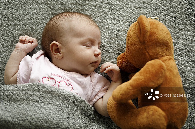 刚出生的女婴和泰迪熊一起睡觉图片素材