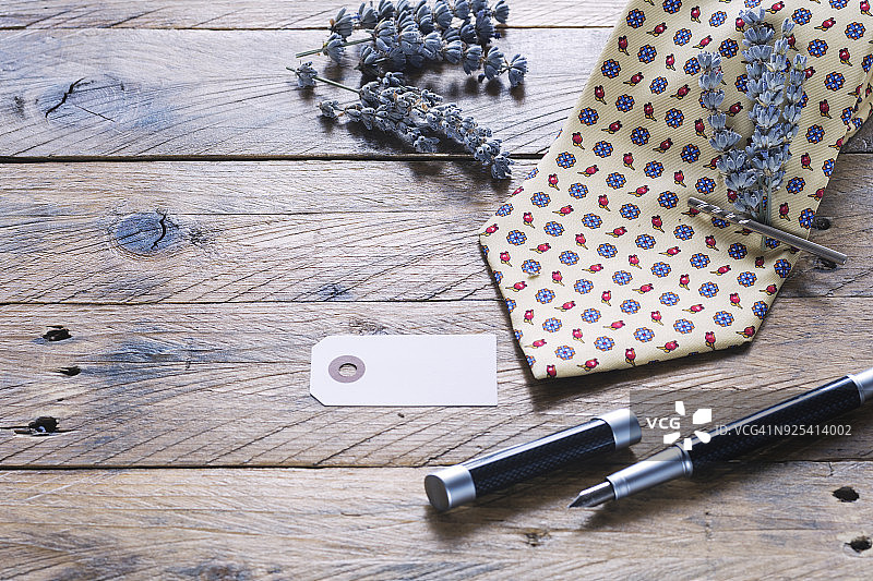 父亲节的概念。领带与薰衣草花束与银领带夹，空白贺卡的信息和钢笔在乡村木制背景。选择性聚焦和复制空间。图片素材