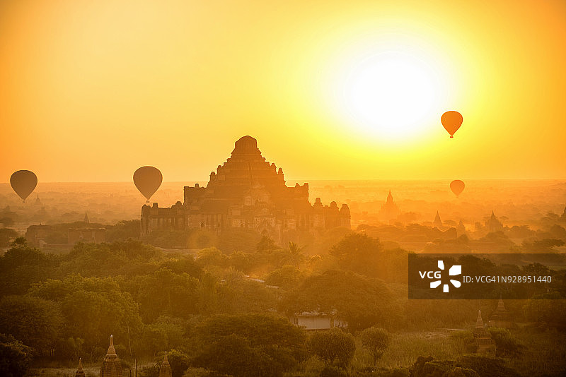 在缅甸蒲甘，游客乘坐热气球飞过古塔，在古城上空观看日出图片素材