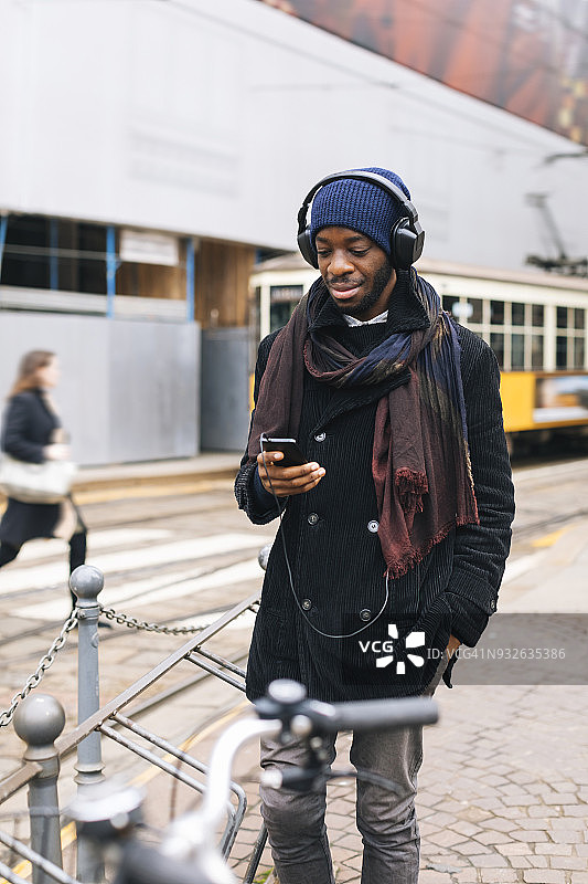 非裔美国人，戴着智能手机和耳机图片素材