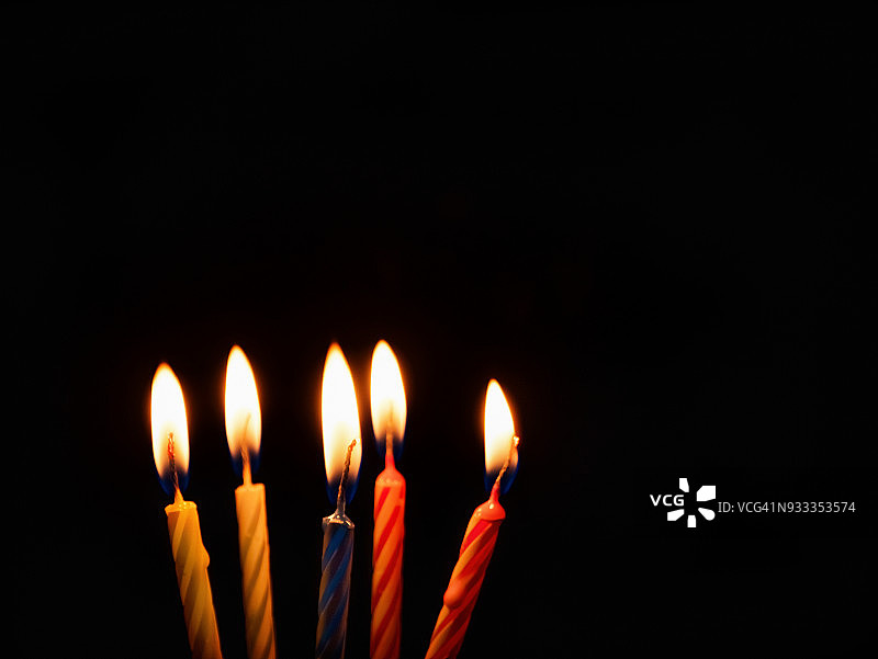 生日蜡烛正在燃烧，在黑色的背景上。图片素材
