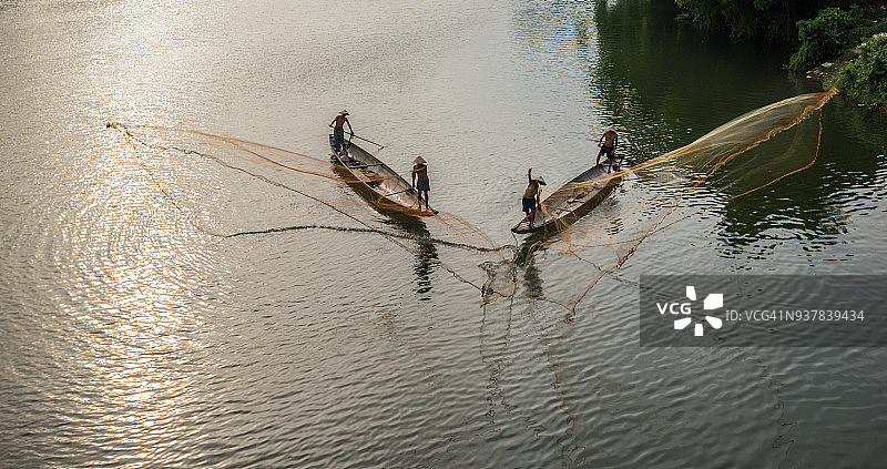 越南顺化，渔民将渔网撒在渔船上捕鱼。图片素材