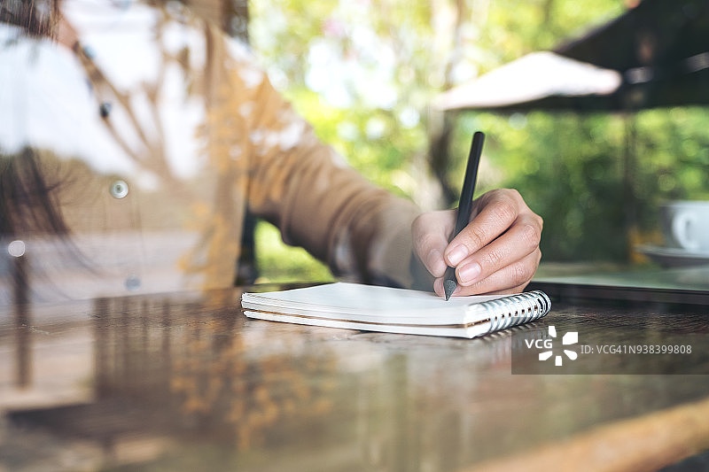 一个女人的手写在一个空白的笔记本和笔记本木桌子上的特写图像图片素材