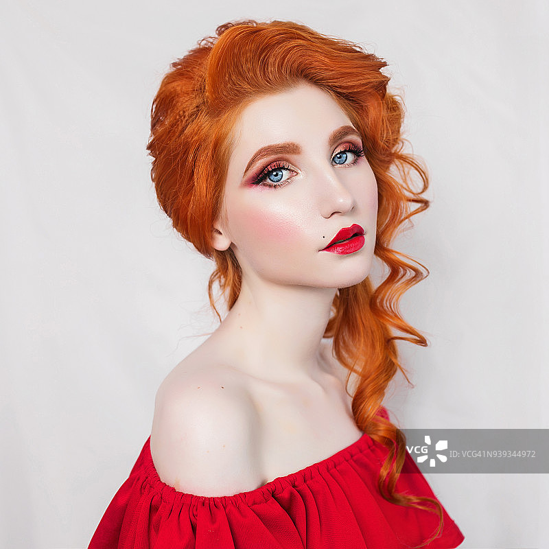 美丽的红发女孩在白色的背景上摆姿势。一个红头发女人的肖像图片素材