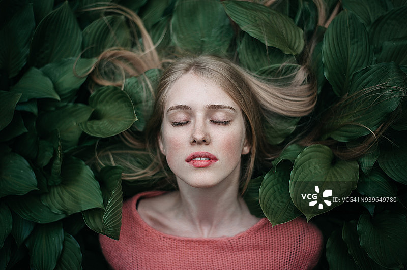 一个躺在绿叶上的女人的肖像图片素材