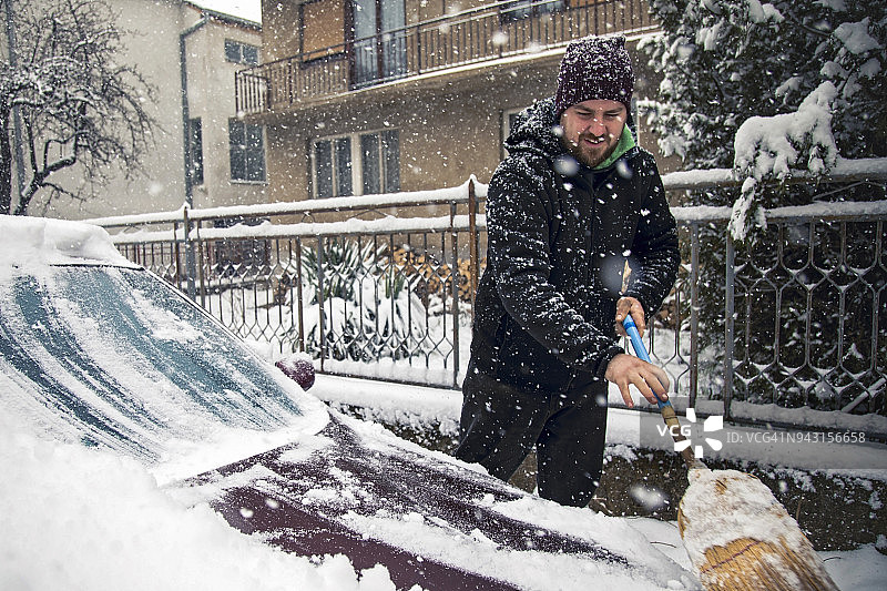 年轻人清理车上的积雪图片素材