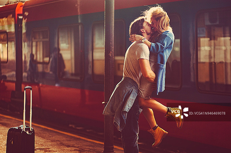 热情洋溢的青年男女在火车站的火车旁边热吻图片素材