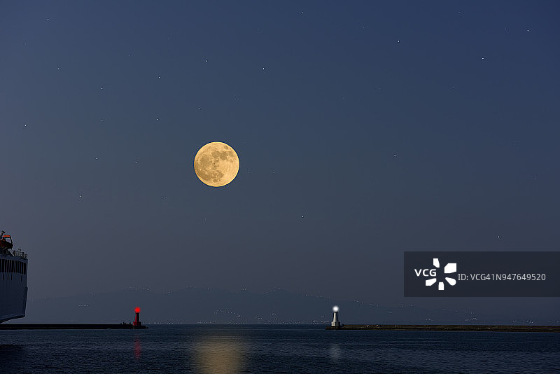 满月在海面和灯塔上升起图片素材