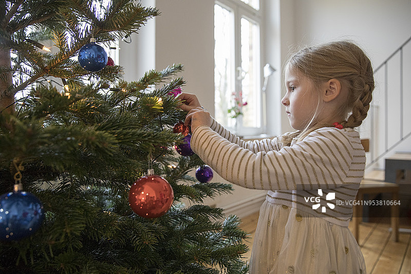 年轻的金发女孩在家装饰圣诞树图片素材
