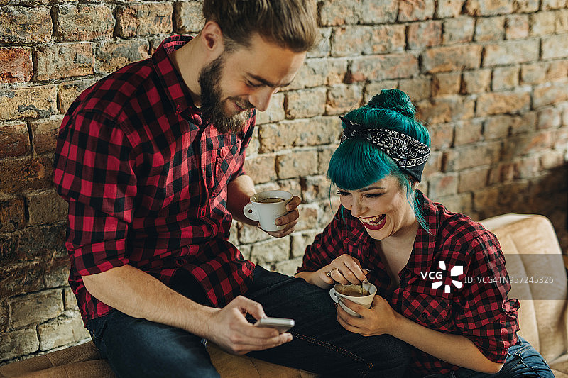 一对幸福的情侣在咖啡馆里看手机短信。图片素材