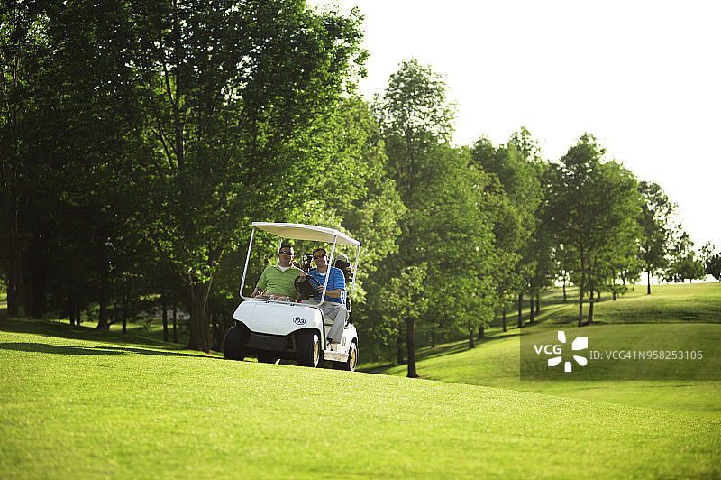 在球场上驾驶高尔夫球车的男性高尔夫球手图片素材