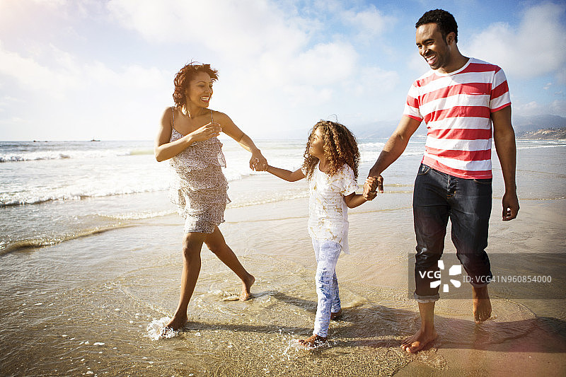 幸福的家庭手牵着手在海滩上散步图片素材
