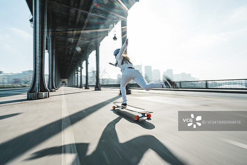 在城市的桥下玩滑板的女人对着天空的模糊运动图片素材