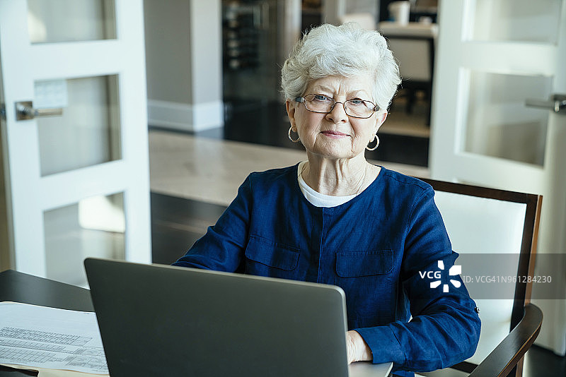 年长妇女在家使用笔记本电脑的肖像图片素材