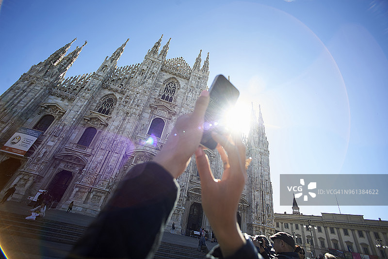 裁剪图像的女人拍摄米兰大教堂对清澈的蓝色天空图片素材