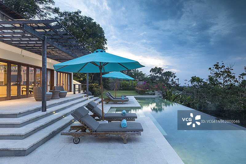 日落时分，在巴厘岛配有游泳池的豪华别墅灯火辉煌图片素材