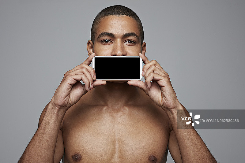 一名男子将智能手机放在嘴边图片素材