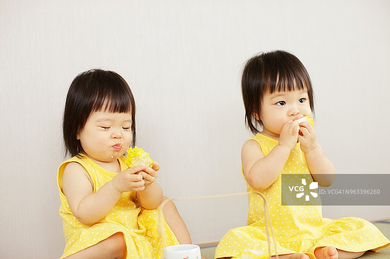 双胞胎姐妹,吃玉米图片素材