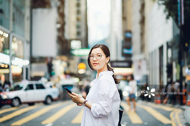 聪明的亚洲女商人在繁忙的市中心街道上使用手机的肖像图片素材