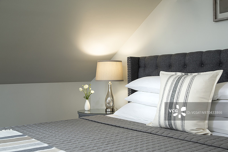 在现代卧室内饰有软垫的床与堆叠的枕头的近距离与粉刷墙壁和灰色配色方案图片素材