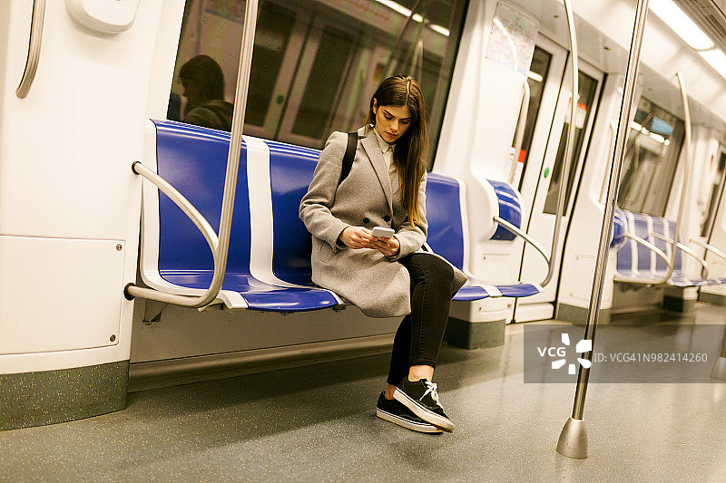 西班牙，巴塞罗那，一个女人坐在地铁里用手机图片素材