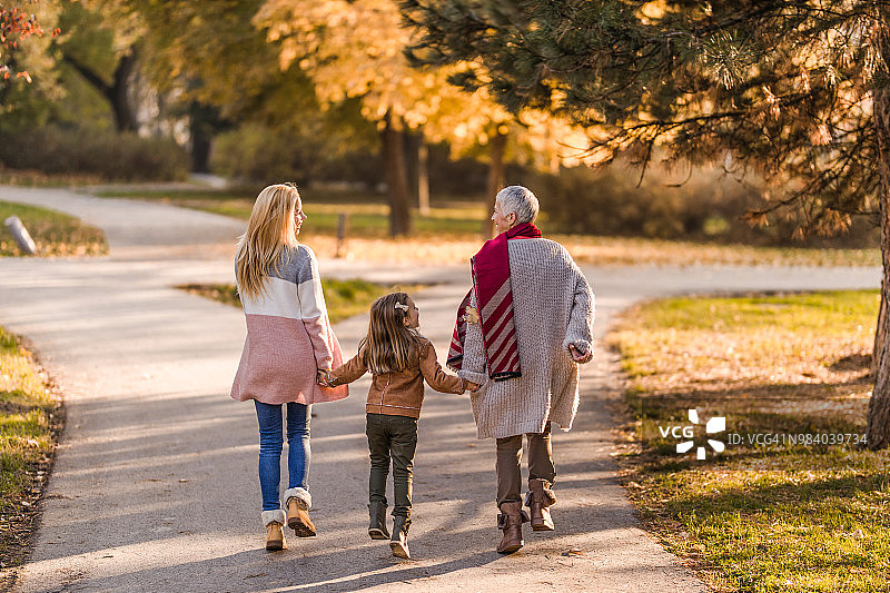 后视图悠闲的母亲，女儿和祖母跑步在秋天的一天。图片素材