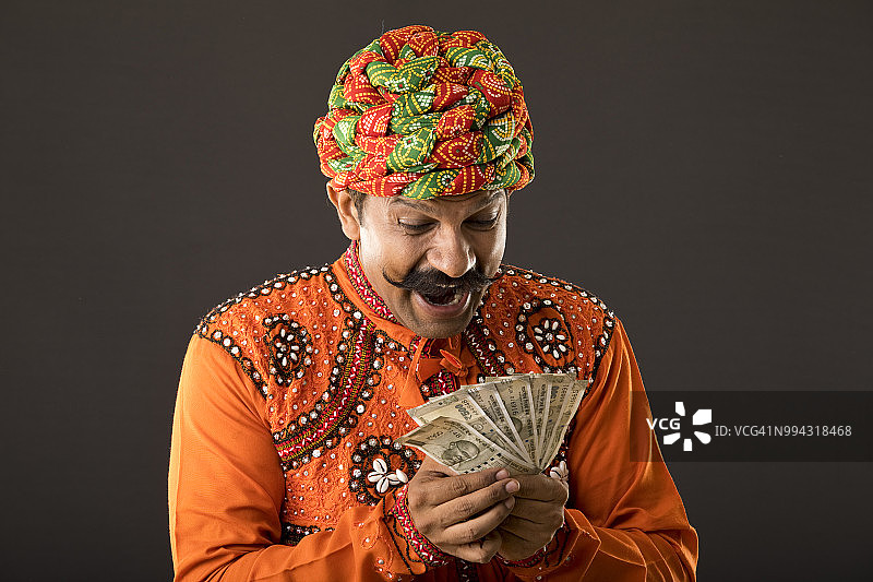 穿着传统服装手持纸币的印度人图片素材