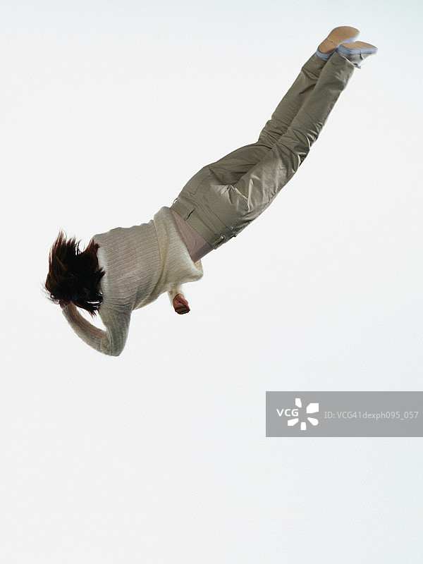 年轻的亚洲女人在裤子和运动衫，跳在半空中图片素材