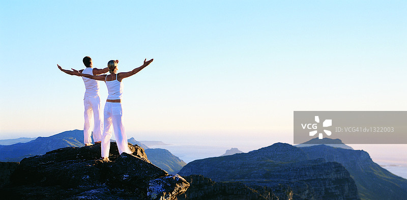 两个年轻人站在山顶上冥想图片素材