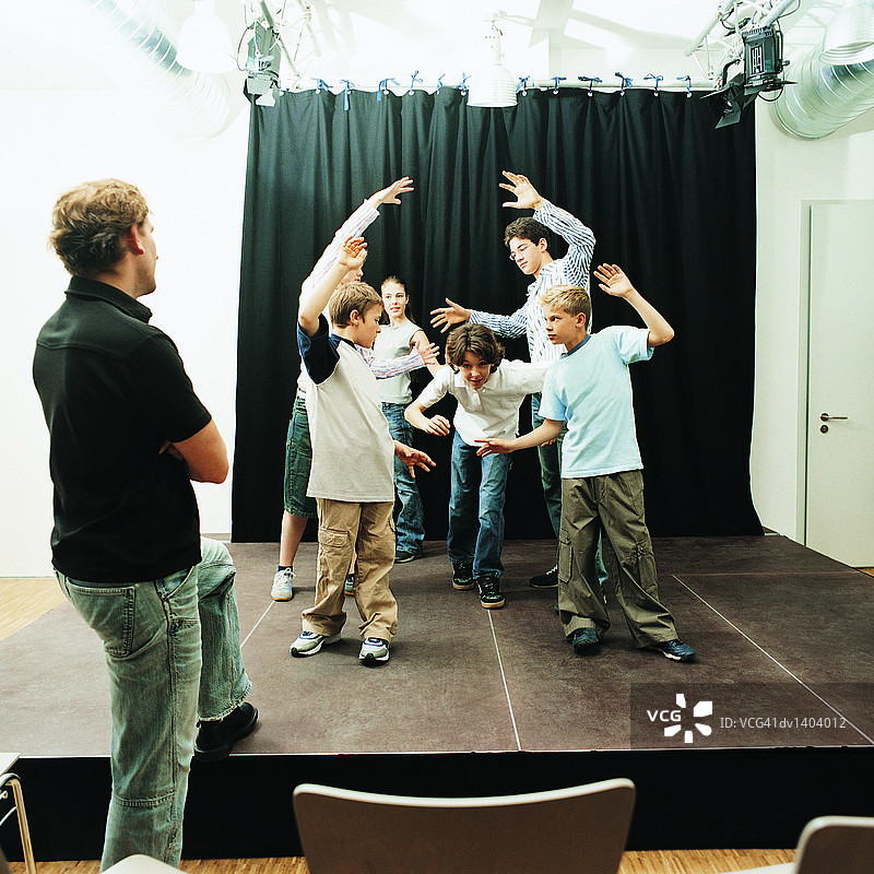戏剧老师观看学童在舞台上表演图片素材