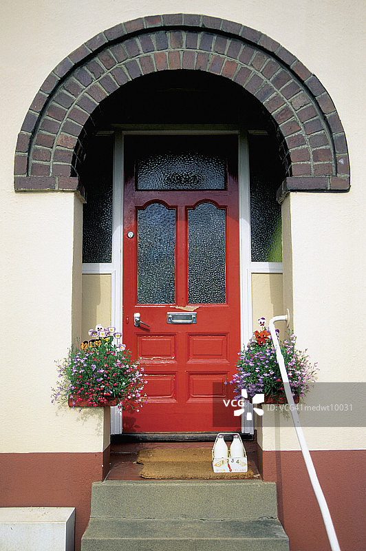 在英国托特内斯，红色门的房子外面挂着牛奶瓶和植物图片素材