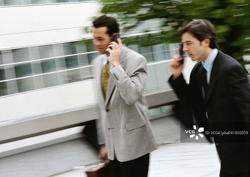 两个商人在外面用手机，模糊不清图片素材