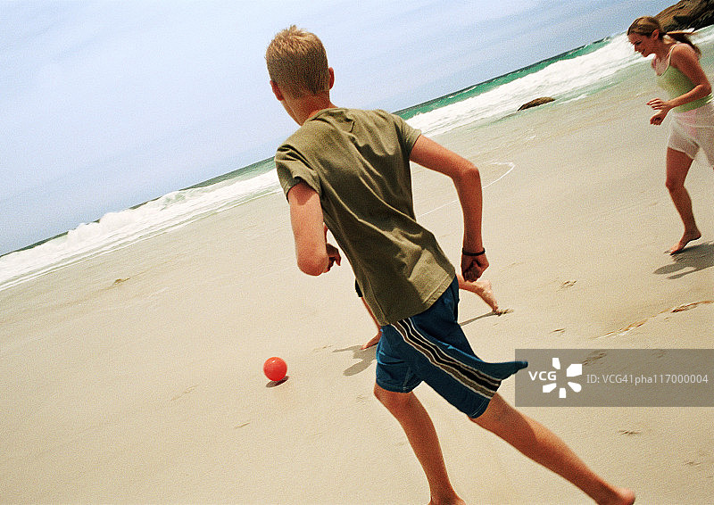 青少年在海滩上踢足球图片素材