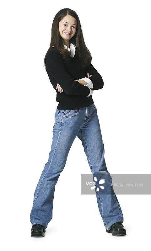 一个穿着牛仔裤和黑色毛衣的十几岁的亚洲女性折叠着她的胳膊和微笑的态度图片素材
